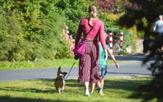 Frau in gestreiften Hosen geht mit ihrem Hund Gassi